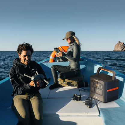 Two people on a boat with aJackery Explorer 1500 Ultra Portable Power Station and camera equipment.