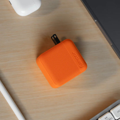 Jackery 102W GaN 3-Port Fast Charger on a wooden desk with computer equipment.