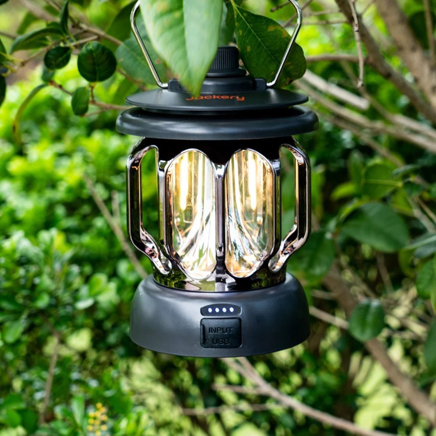 Jackery Camping Lantern with reflective interior hanging among green leaves