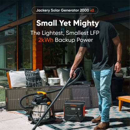 Jackery Explorer 2000 v2 Portable Power Station with vacuum plugged in and solar panel in the background