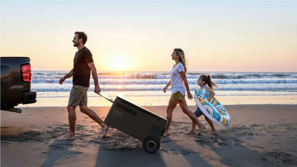 Man pulling the Anker SOLIX EverFrost 2 Electric Cooler 58L on a trolley beside the beach with two others